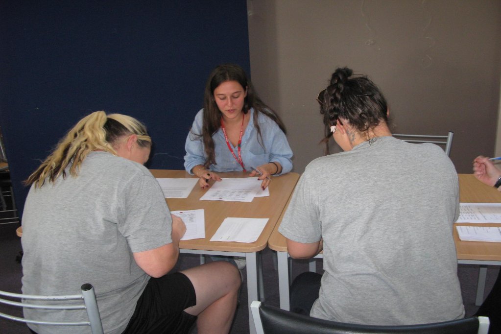 Two women work with a trainer at a table.