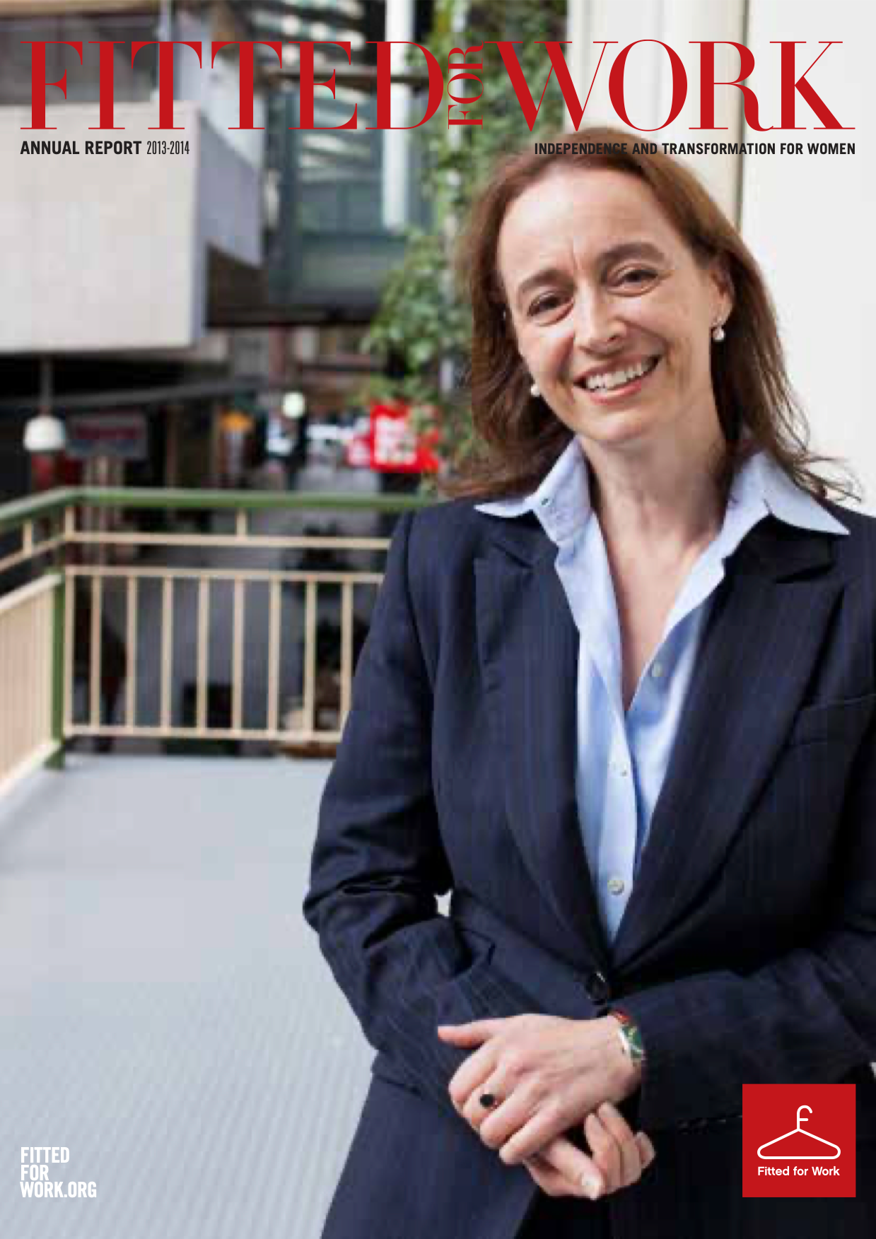 A smiling women standing in a relaxed position on the balcony outside Fitted for Work's office. She is wearing professional clothing