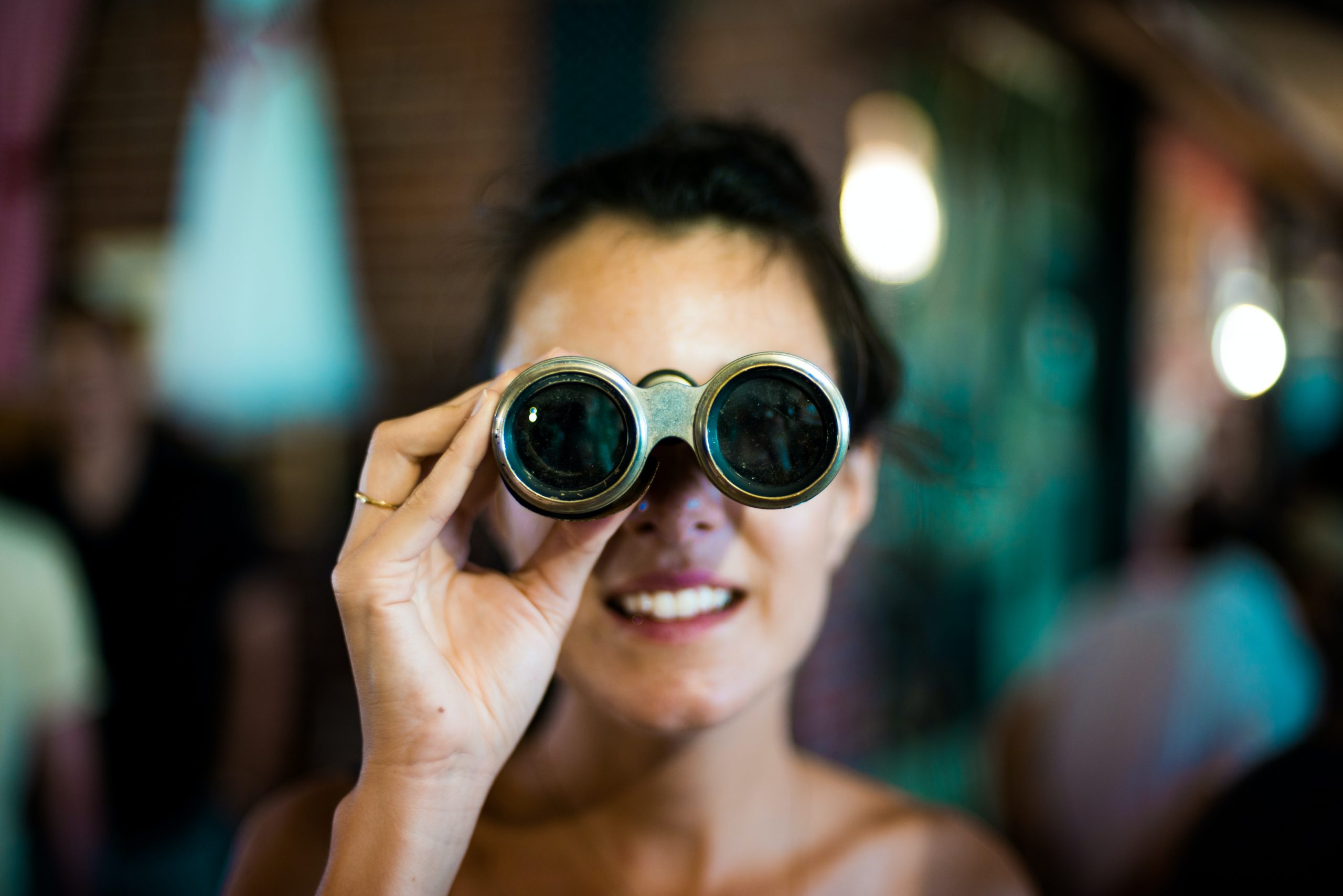 A young woman looks through a pair of binoculars.