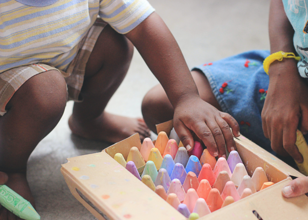 A close up image of children's hands playing with chalk