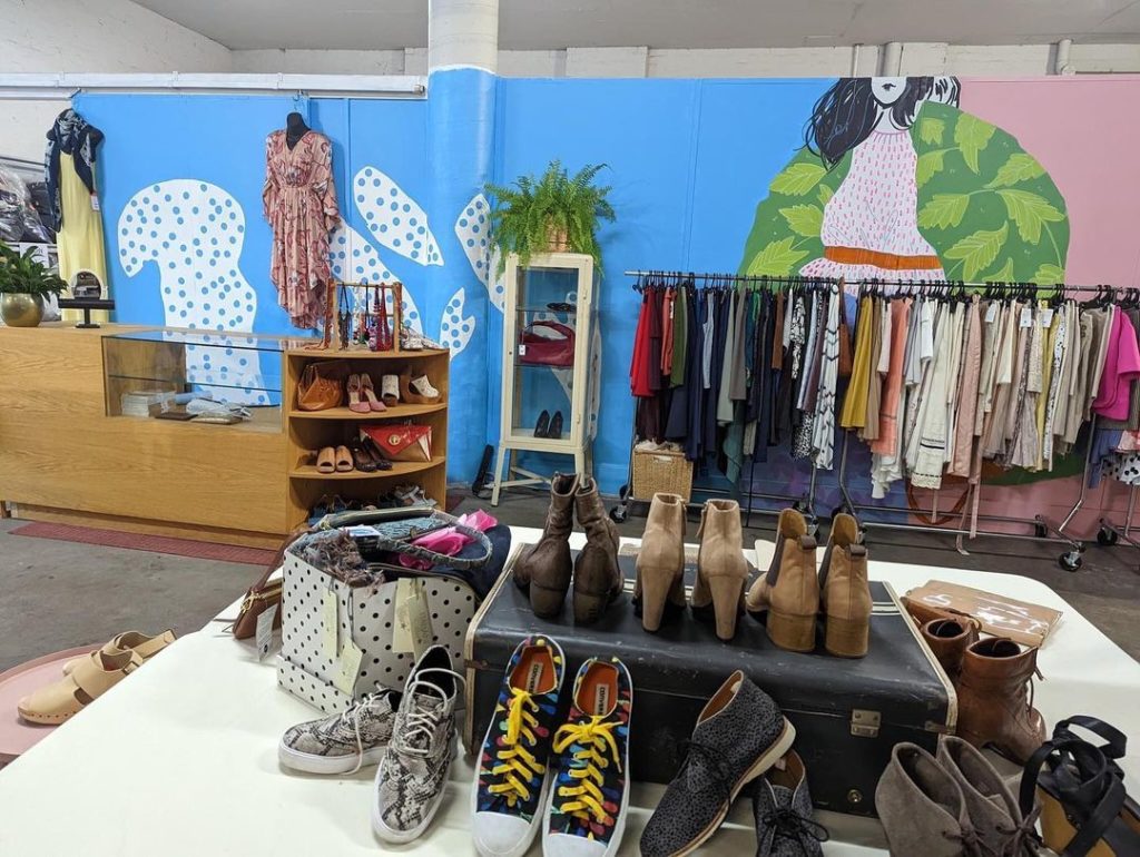 The Conscious Closet store space, shows stylish clothing displayed in front of a colourful wall mural