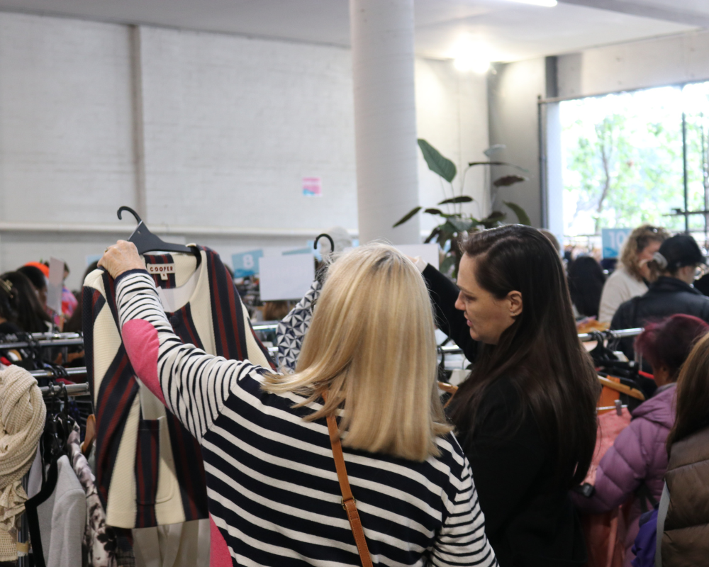 Two shoppers hold up a jacket in The Conscious Closet.